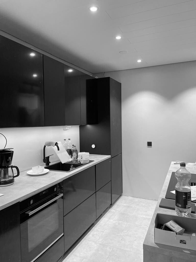 A renovated dark island kitchen with recessed ceiling downlights and under-cabinet lighting.